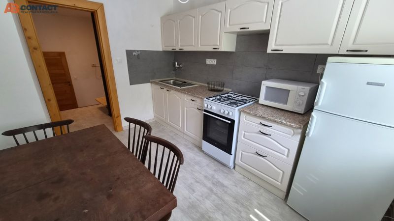 Küche in einer 2-Zimmer-Wohnung mit Holztisch, Mikrowelle und Gasherd.