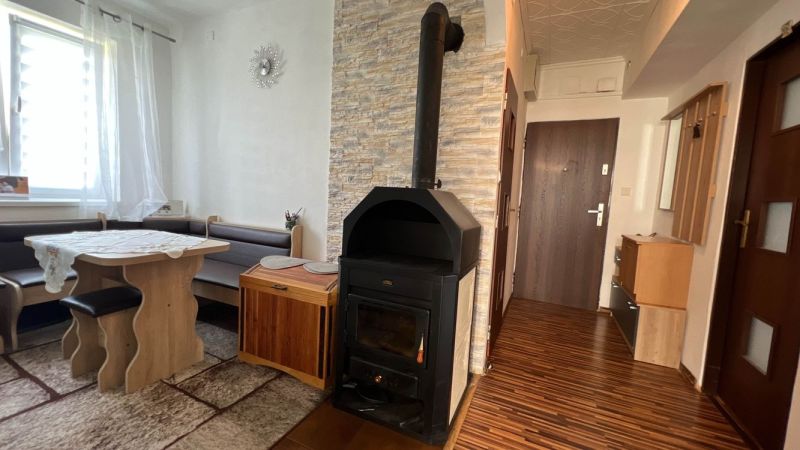 Innenraum einer 3-Zimmer-Wohnung mit einem Kaminofen und einem Boden in Holzoptik.