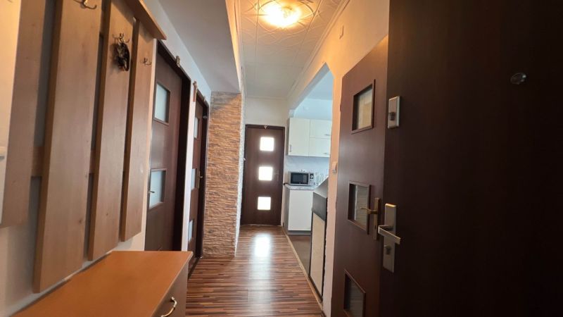 Eingangsflur in einer 3-Zimmer-Wohnung mit Holzboden und Küche im Hintergrund.