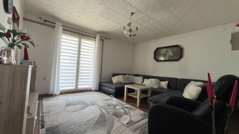 Wohnzimmer in einer 3-Zimmer-Wohnung mit großem Sofa, Holzboden und Dekorationen.