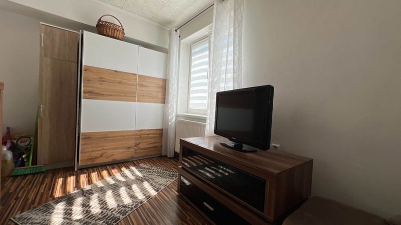 Ein Zimmer in einer 3-Zimmer-Wohnung mit einer Kommode, einem Fernseher und einem Boden mit Holzdekor.