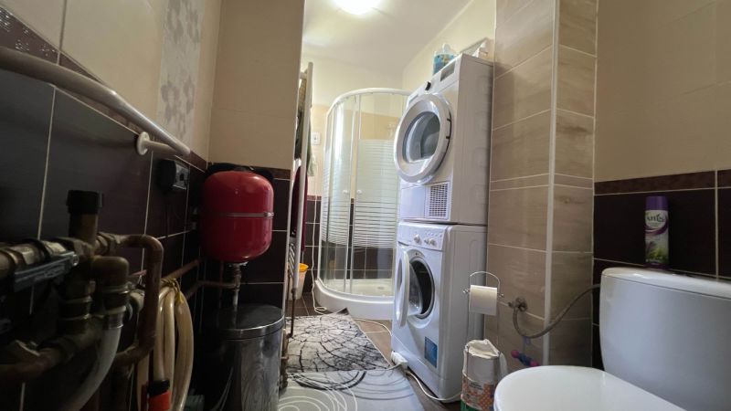 Badezimmer in einer 3-Zimmer-Wohnung mit Waschmaschine, Duschkabine und Installationen.