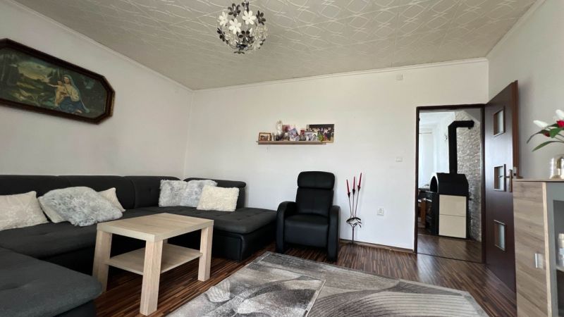 Wohnzimmer in einer 3-Zimmer-Wohnung mit Holzboden, bequemen Sitzgelegenheiten und Dekoration.