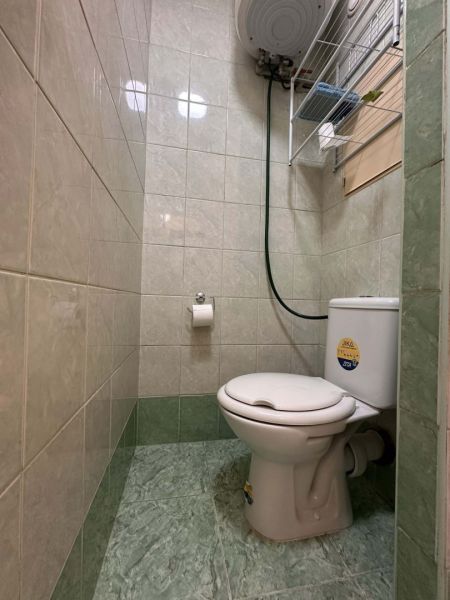 Toilette in einem Ferienapartment mit Fliesen bis zur halben Wand, grüne Fliesen.