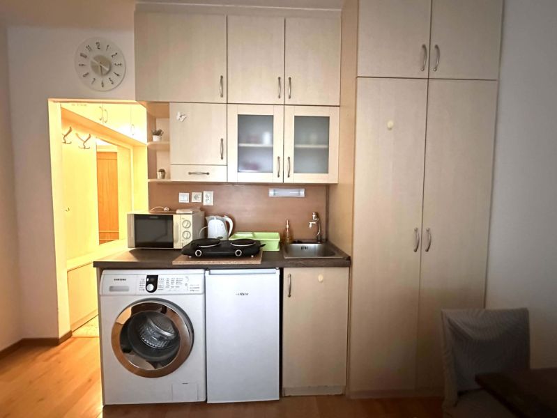 Küche in einer Ferienwohnung mit Küchenzeile und Waschmaschine, Boden mit Holzdekor.