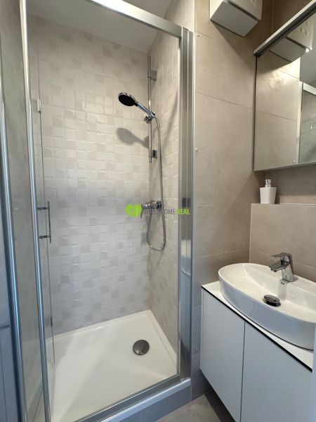Duschkabine mit Keramikfliesen im Badezimmer des Einzimmerapartments.