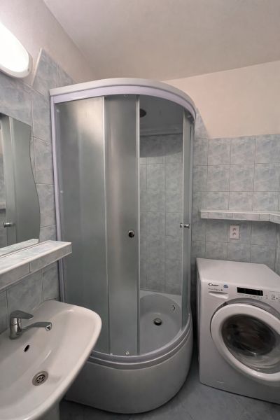 Badezimmer mit Dusche und Waschmaschine in einer 2-Zimmer-Wohnung.