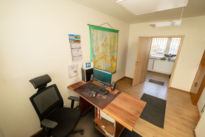 Ein Büro mit einem Tisch und einem Computer, ein Boden mit Holzdekor, besondere Immobilien.