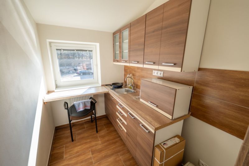 Küche mit Schränken in Holzoptik und Tisch, Besondere Immobilien.