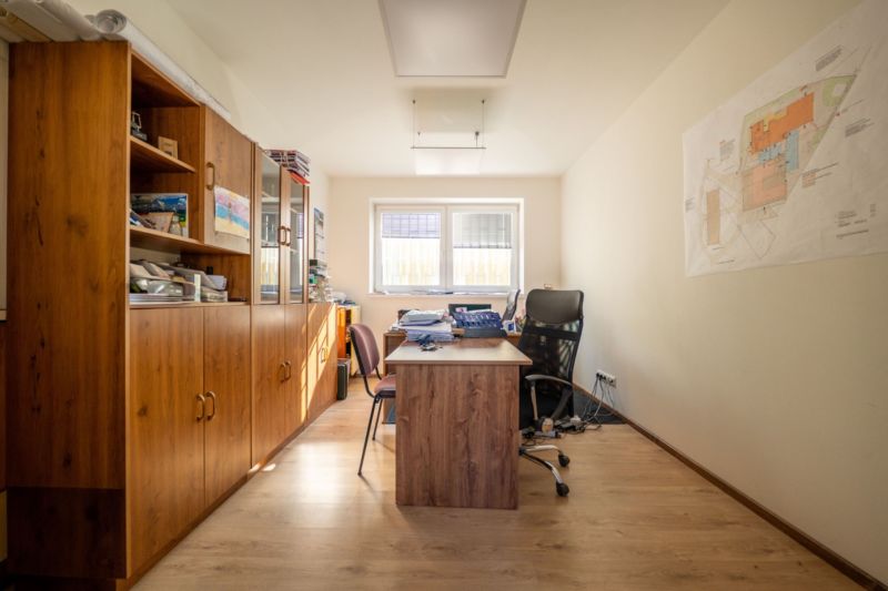 Ein Büro mit einem Tisch, Stühlen, einem Schrank und einem Boden mit Holzdekor. Besondere Immobilien.