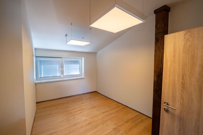 Ein Raum mit einem Boden in Holzdekor und quadratischen Leuchten, besondere Immobilien.