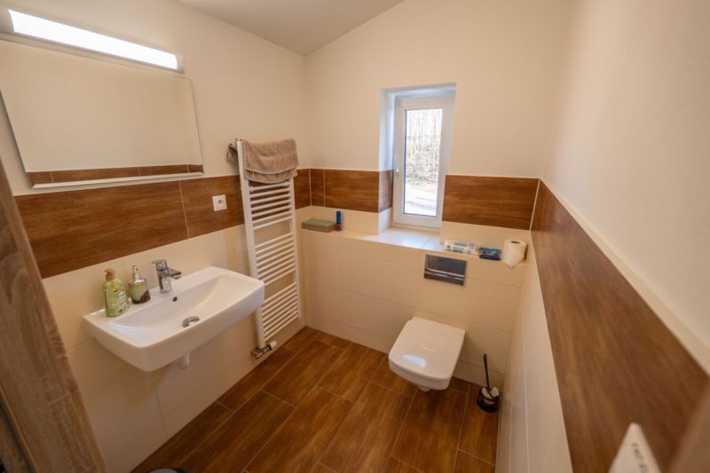 Badezimmer mit Toilette, Waschbecken und Boden mit Holzdekor in besonderen Immobilien.