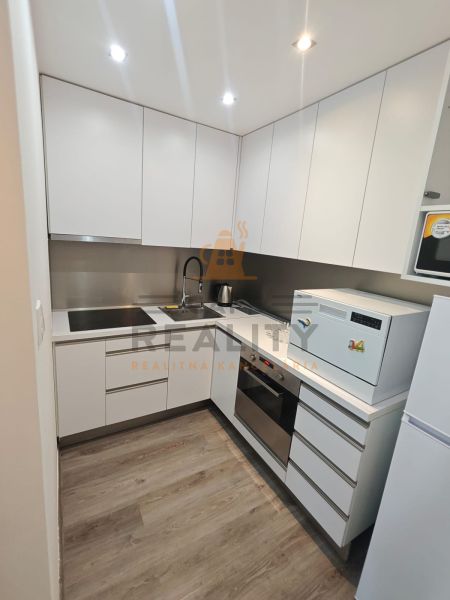 Küchenzeile in einer Einzimmerwohnung mit Geräten und einem Boden in Holzoptik.
