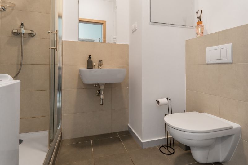 Badezimmer mit Toilette und Duschkabine in einer Einzimmerwohnung.