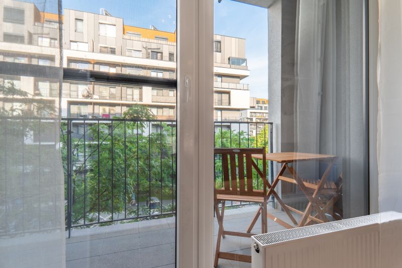 Blick aus einer Einzimmerwohnung auf den Balkon mit Tisch und Stühlen.