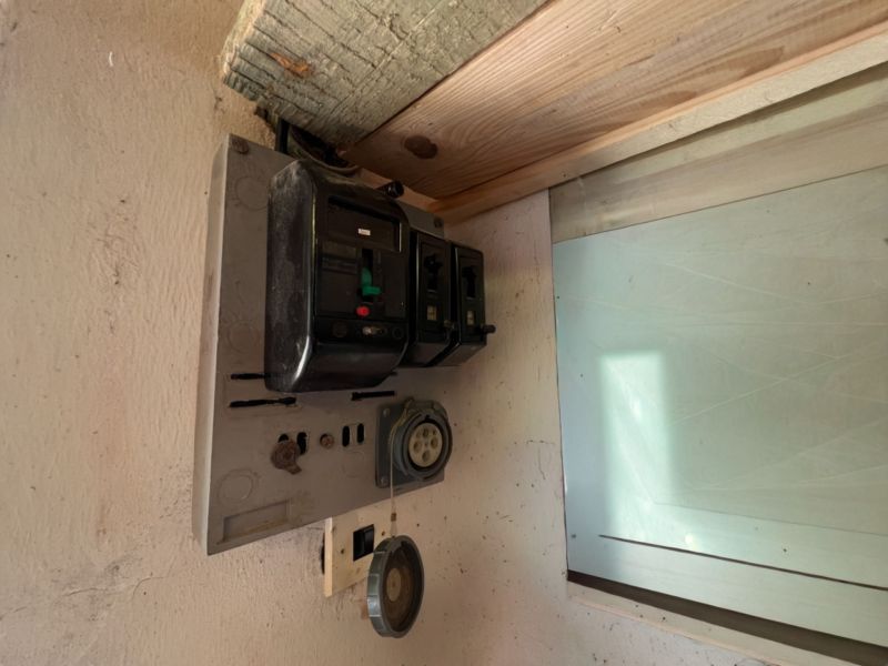 Alter elektrischer Verteilerkasten in der Garage, mit alten Sicherungen und Steckdosen.