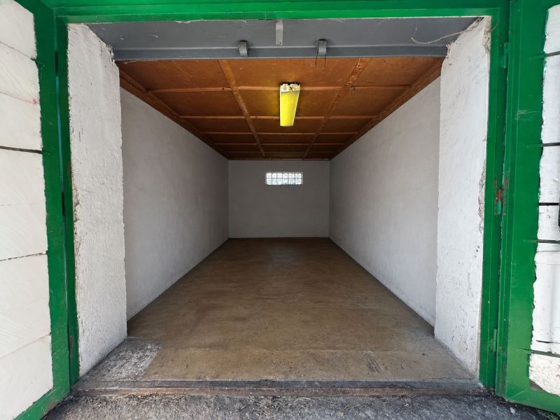 Offene Garage mit Holzdecke und Betonboden.