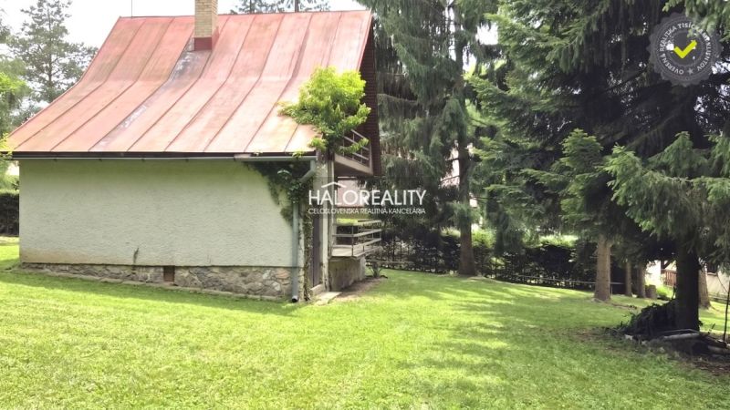 Eine Hütte in Ružiná mit einem Blechdach, umgeben von Bäumen und Rasen.