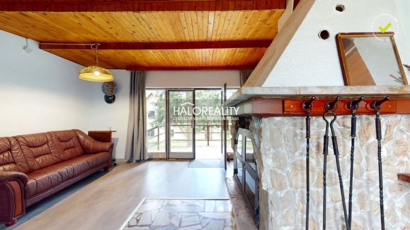 Rustikales Interieur einer Hütte mit Kamin, Ledersofa und Holzboden.