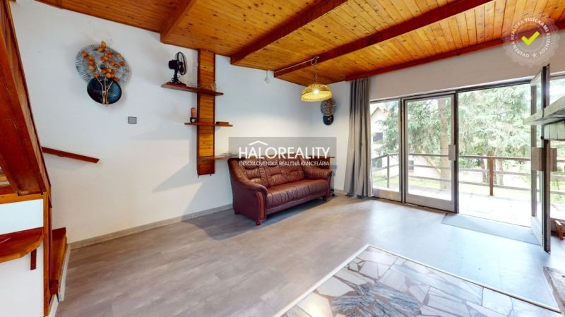 Ein Interieur mit einer Holzdecke, einem bequemen Sofa und Glastüren in einer Hütte.