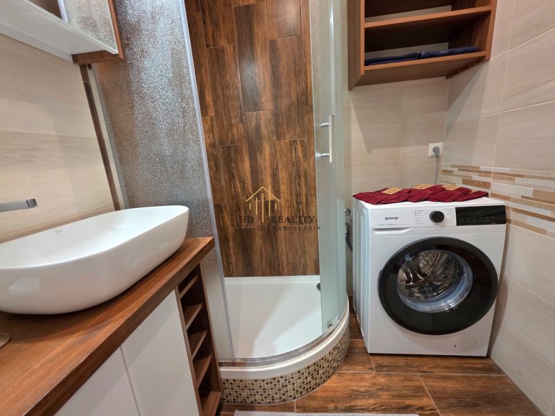 Badezimmer in einer 2-Zimmer-Wohnung mit Waschmaschine und Boden in Holzoptik.