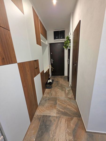 Der Flur in der 2-Zimmer-Wohnung mit dunklen Türen und einem Boden in Holzoptik.