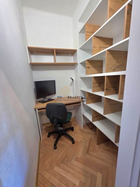 Arbeitsbereich mit Holzboden und Regalen in einer Zweizimmerwohnung.