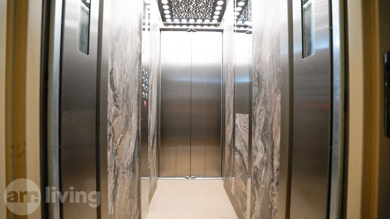 Interieur eines Aufzugs mit Marmorverkleidung und verspiegelten Wänden.