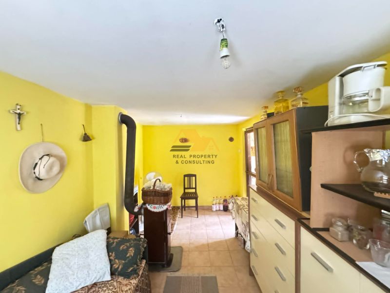 Das Innere der Hütte mit hellgelben Wänden, einem Sofa, einem Schrank und einem Herd.