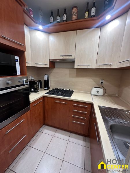 Küche mit Eckküche und Geräten in einer 3-Zimmer-Wohnung, Keramikfliesen.