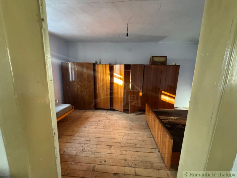 Ein Zimmer in einem Einfamilienhaus mit Holzmöbeln und einem Bett auf dem Boden mit Holzdekor.
