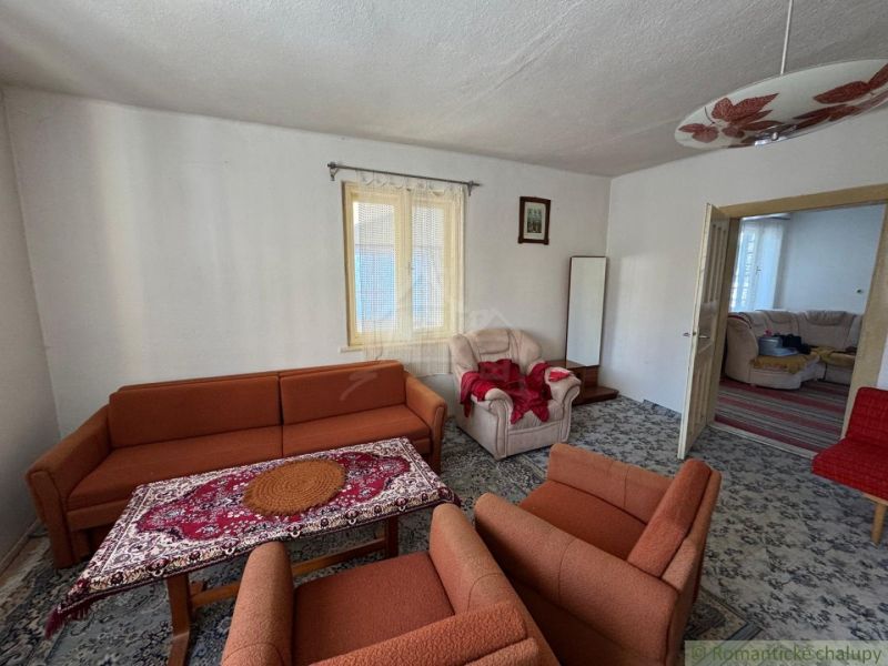 Wohnzimmer in einem Einfamilienhaus mit einem orangefarbenen Sofa und einem gemusterten Teppich.