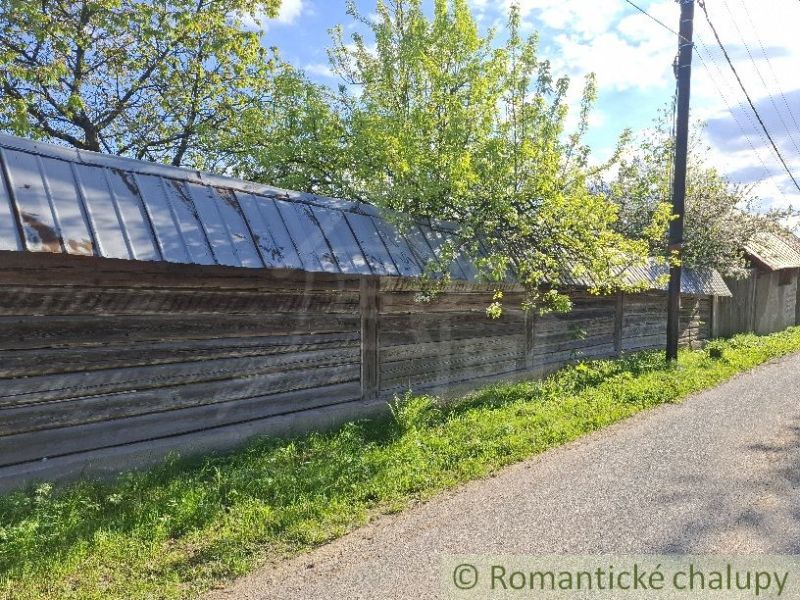 Ein Holzzaun bei einem Einfamilienhaus in Šumiac, umgeben von Bäumen und einer Straße.