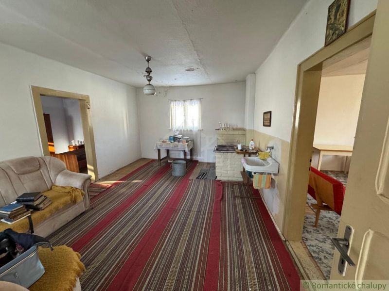Interieur eines Einfamilienhauses mit älteren Möbeln, einem gestreiften Teppich und einem Sofa.