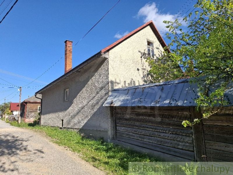 Ein Einfamilienhaus in Šumiac mit einem Blechdach, angrenzend an die grüne Natur und die Straße.