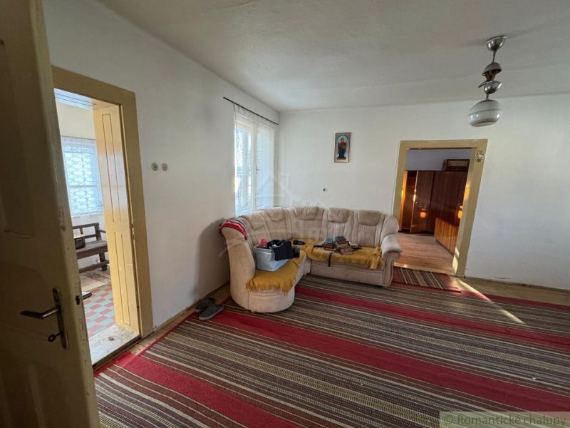 Ein Einfamilienhaus mit Teppich, beigem Sofa, Türen und einem Bild an der Wand.