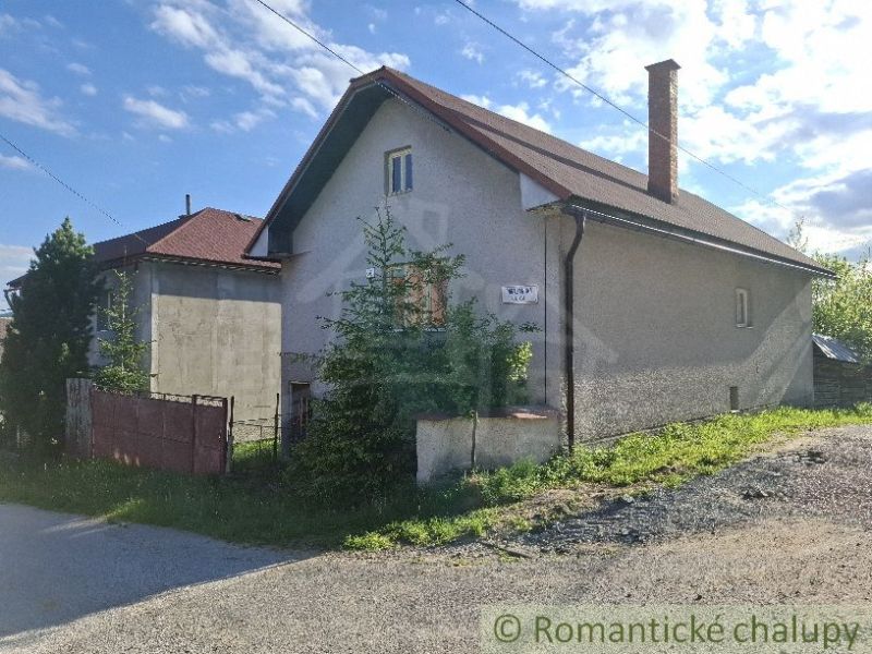 Ein Einfamilienhaus in Šumiac mit einem Blechdach und einem Garten an der Straße.