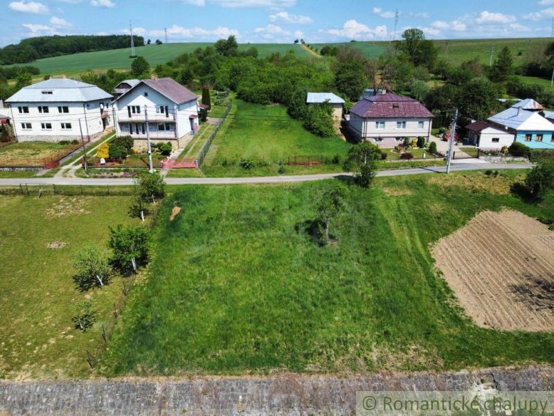 Grundstücke - Wohnen in Karnej: Grünflächen, Häuser und Zufahrtsstraße unter blauem Himmel.