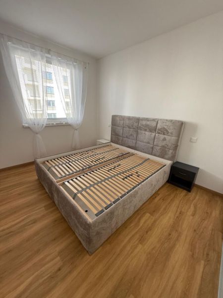 Schlafzimmer in einer 2-Zimmer-Wohnung mit Holzboden und großem Bett.
