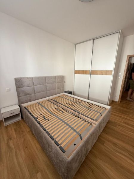 Schlafzimmer mit Bett, Schrank und Holzboden in einer 2-Zimmer-Wohnung.