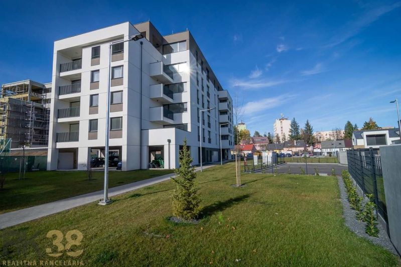 Ein Wohnhaus in Poprad mit grünem Rasen und benachbarten Gebäuden im Hintergrund.