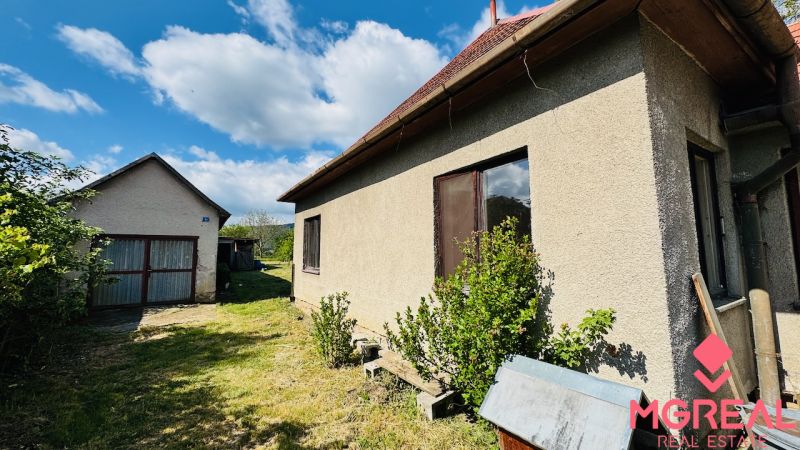 Ein Einfamilienhaus in Pažiti mit Garten und separater Garage unter blauem Himmel.