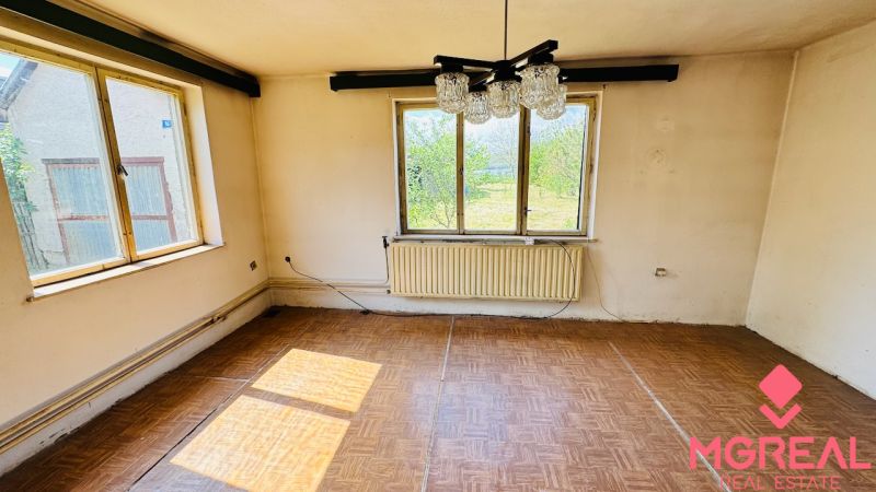 Ein Zimmer in einem Einfamilienhaus mit einem Boden in Holzoptik und großen Fenstern.