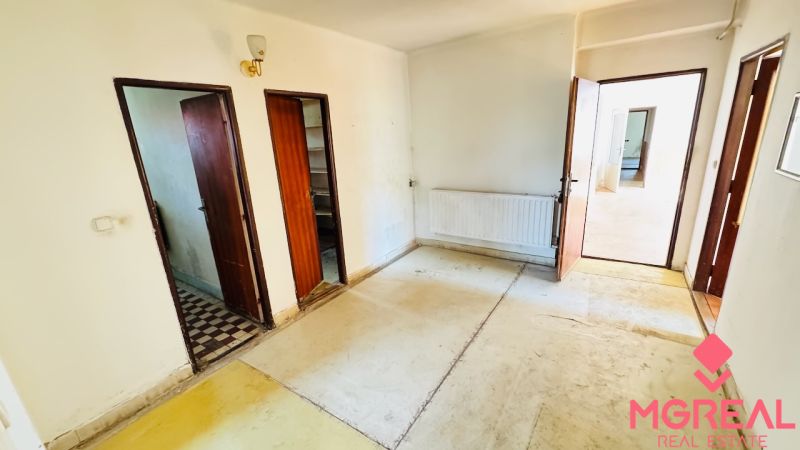 Innenraum mit altem Boden, Holztüren und Heizkörper in einem Einfamilienhaus.