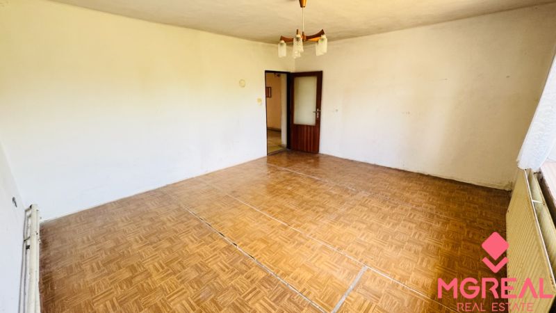 Ein Zimmer in einem Einfamilienhaus mit einem Boden in Holzoptik und einem Kronleuchter.