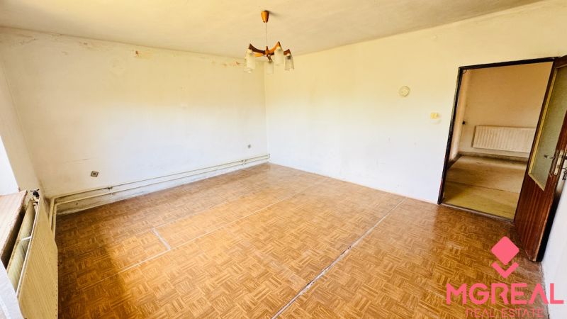 Wohnzimmer in einem Einfamilienhaus mit Holzboden und einfacher Beleuchtung.