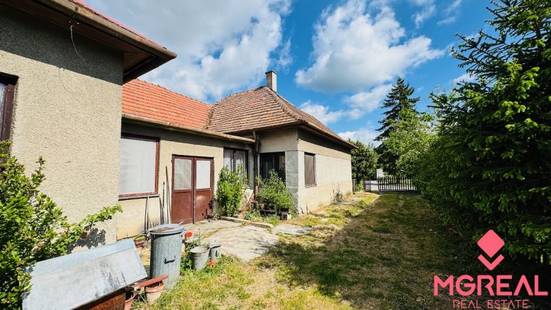 Einfamilienhaus in Pažiť mit zwei Eingängen, Fenster mit Netzen, daneben ein schmaler Garten.