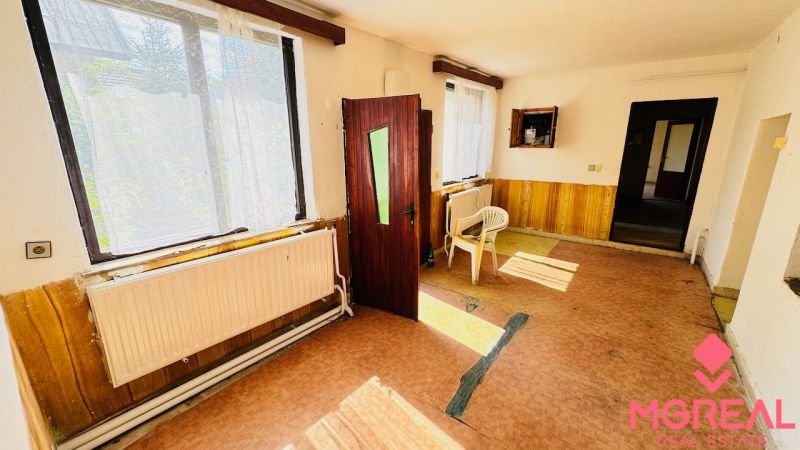 Innenraum eines Einfamilienhauses mit offenen Türen, Plastikstühlen und großen Fenstern.