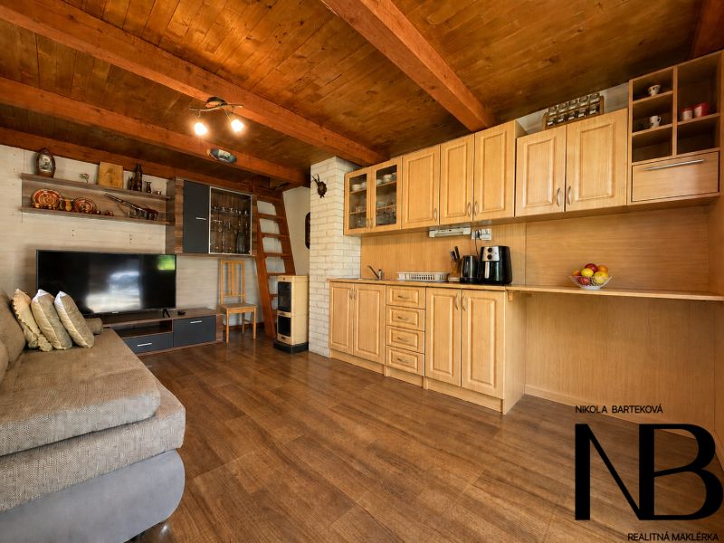 Innenraum einer Hütte mit Küchenzeile, Holzboden und Sofa.