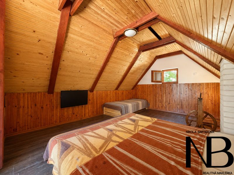 Das Dachgeschoss in der Hütte mit Holzeinrichtung bietet ein Bett und einen Fernseher.